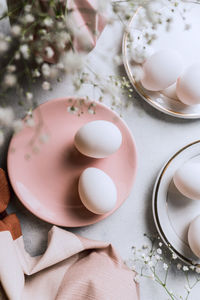 From above still life of beautiful painted easter eggs over white table background near cute flowers