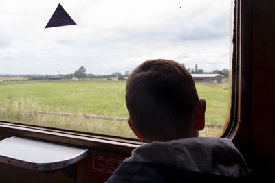 Rear view of man looking through train window