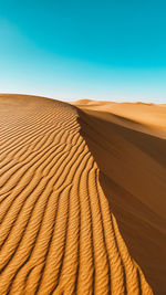 Sand dunes in desert against clear blue sky