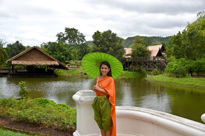 Full length of woman in traditional clothing standing by lake against sky