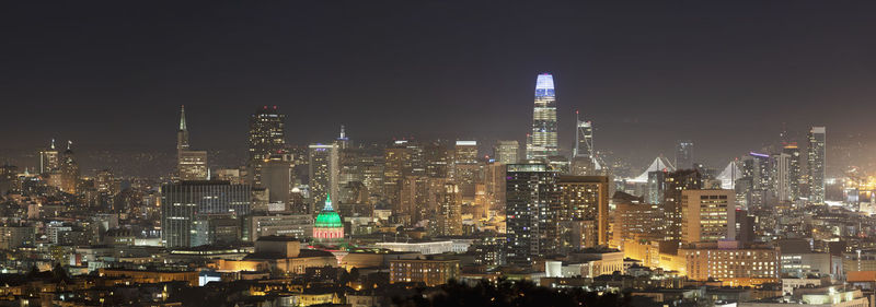 Illuminated buildings in city against sky at night