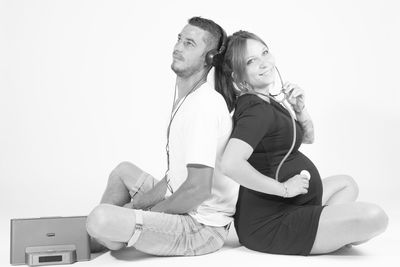 Young couple sitting against white background