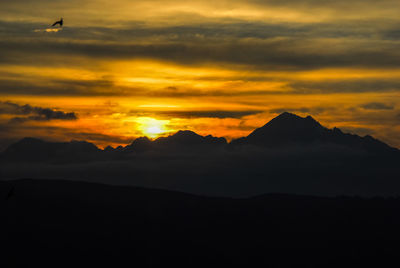 Scenic view of silhouette mountains against orange sky
