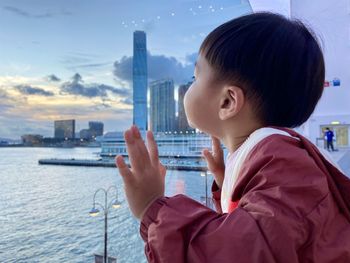Side view of asian boy watching building, harbour view 