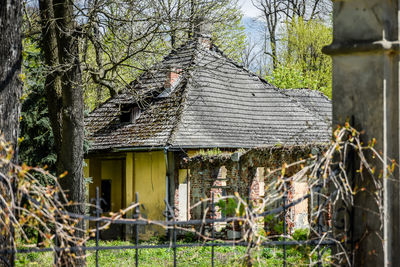 Bare trees by house against sky