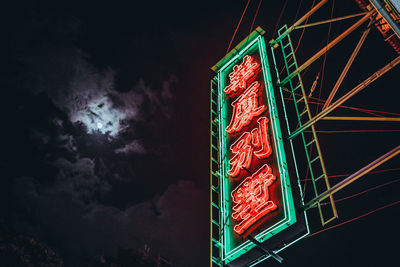 Low angle view of illuminated text against sky at night