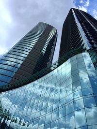 Low angle view of skyscrapers against cloudy sky