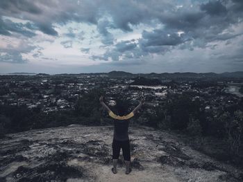 Rear view of man standing on cliff against sky