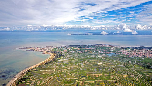 Aerial view of city by sea against sky