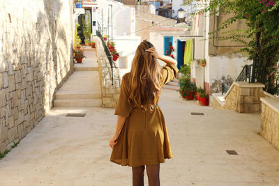 Rear view of woman standing at sidewalk in city