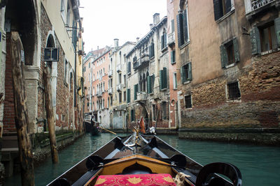 Boats moored in canal amidst buildings against sky