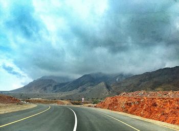 Country road against cloudy sky