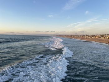 Sea waves rushing towards shore against sky