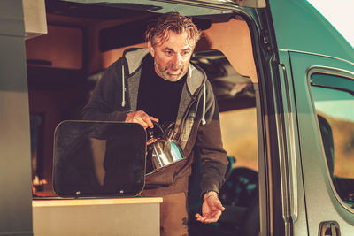 Mature man standing in camping van