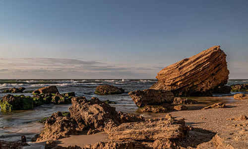 Rock formation on beach against sky