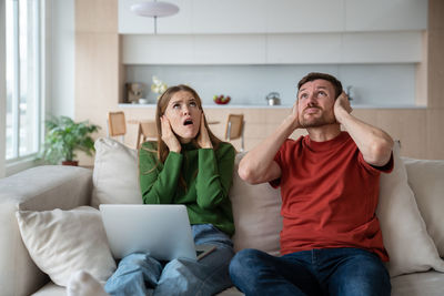 Portrait of siblings sitting on sofa at home