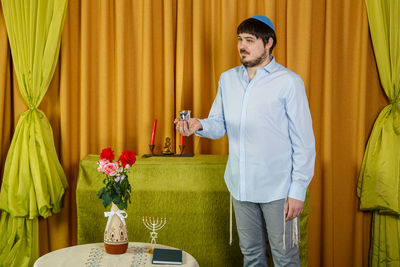 Young man standing by flower vase on table