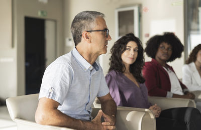 Mature businessman wearing eyeglasses planning strategy with colleagues in office