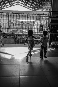 Rear view of people walking on tiled floor