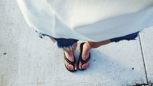 Low section of woman standing on footpath 