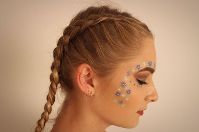 Profile view of woman star shape face paint against wall