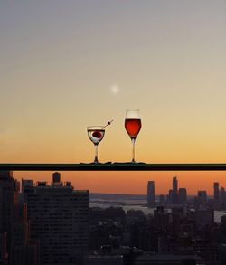 Drinks on retaining wall against sky at sunset