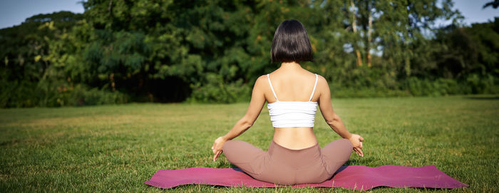 Rear view of woman sitting on grassy field