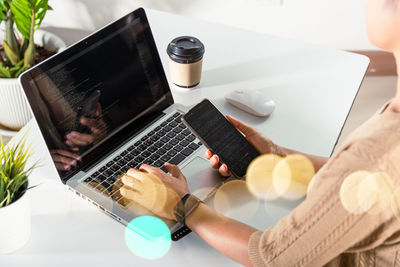 Midsection of woman using laptop on table