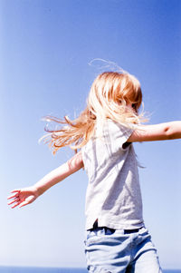 Full length of woman with arms raised against clear sky