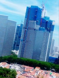 Low angle view of skyscrapers against cloudy sky