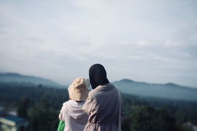 Rear view of friends looking at mountain against sky