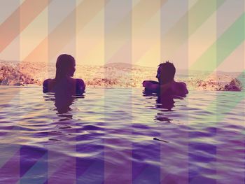 People sitting by swimming pool in sea against sky