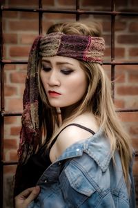 Portrait of young woman standing against wall