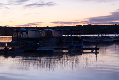 Boats moored in lake against sky during sunset