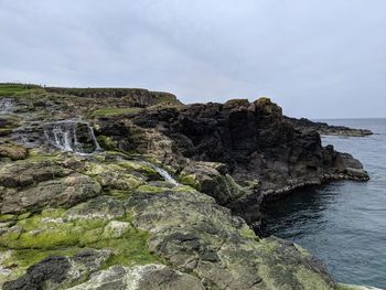 Rock formations on sea shore against sky