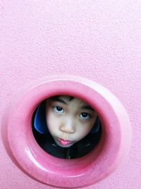 High angle view portrait of cute girl peeking through hole
