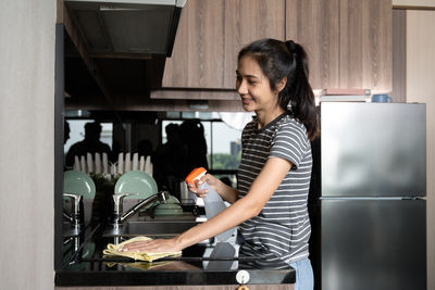 Side view of young woman working in kitchen