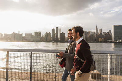 Usa, new york city, two young men walking along east river