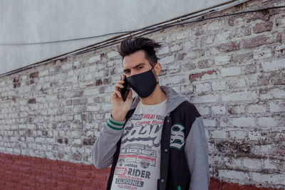 Portrait of young man with face mask in city against clear sky