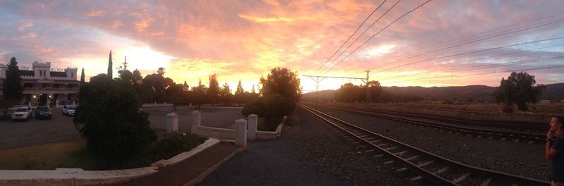 Railroad tracks against cloudy sky at sunset