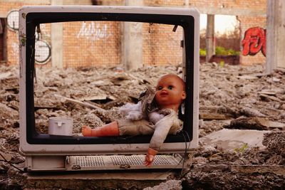 Close-up of abandoned doll and television set outdoors