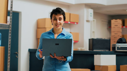 Young woman using digital tablet while standing in office