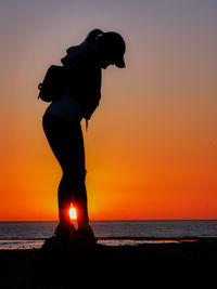 Silhouette man standing on beach during sunset