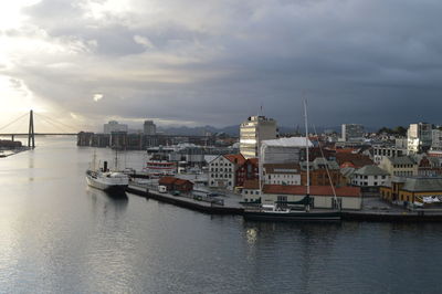 Sailboats moored on harbor in city against sky