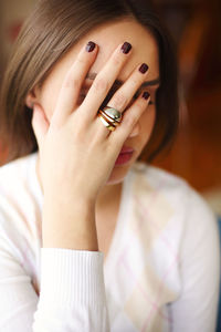 Close-up of woman covering face with hand