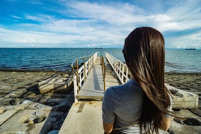 Rear view of woman looking at sea against sky