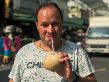 Portrait of mid adult man having drink while standing on street in city