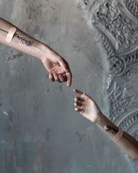 Cropped hands of couple with flowers against wall