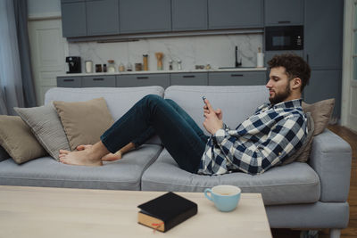Young woman using laptop while sitting on sofa at home
