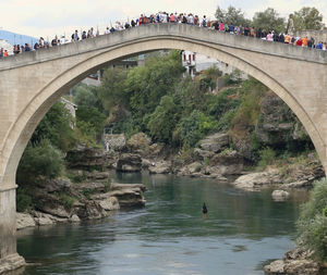 People on bridge over river against sky